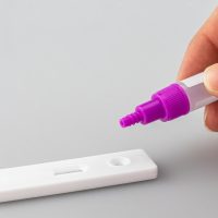 中年男性技术编辑在武昌汽车维修车间内手持检测工具，身后是举升机与工具墙